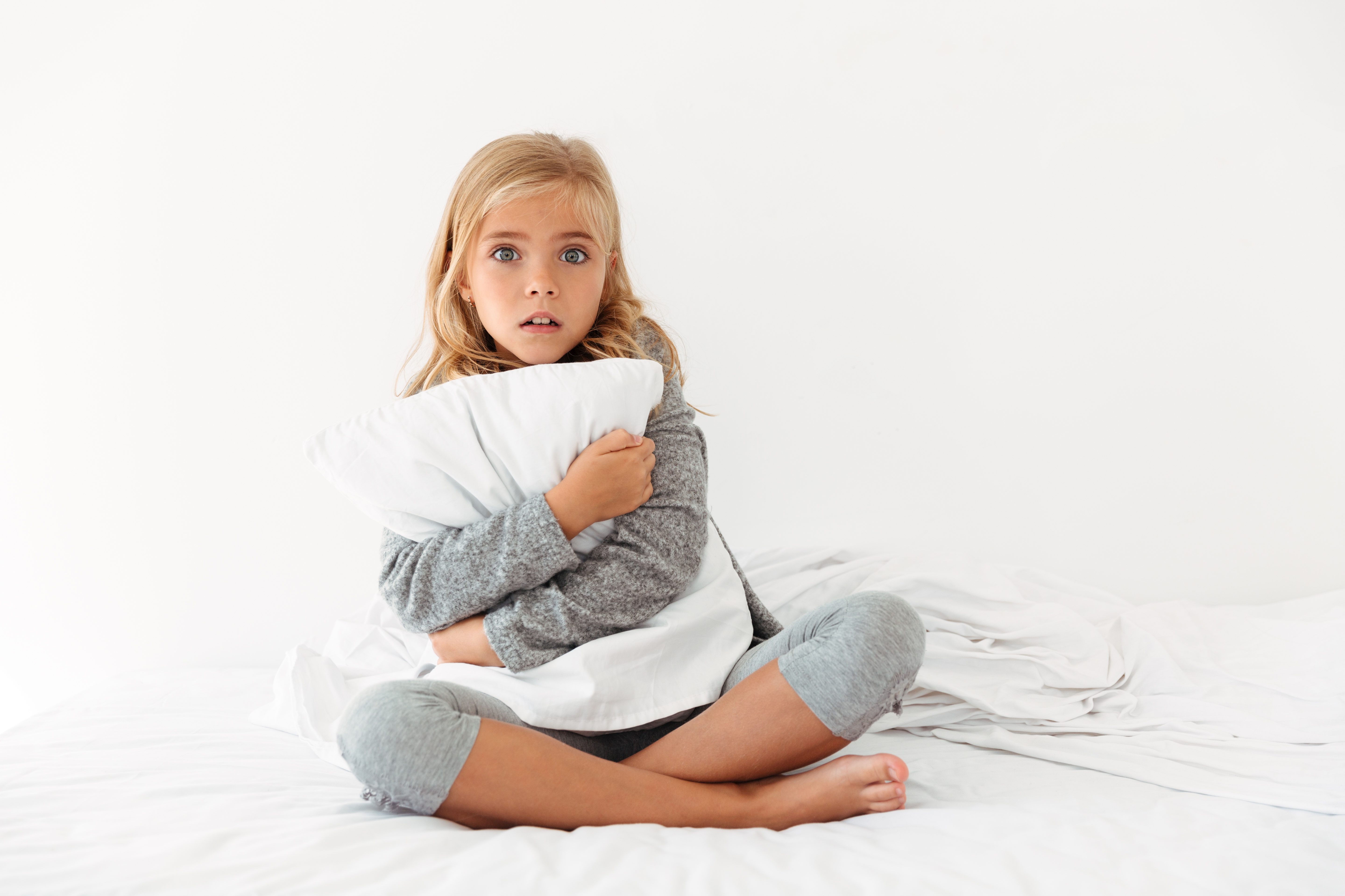 portrait-scared-little-girl-hugging-pillow